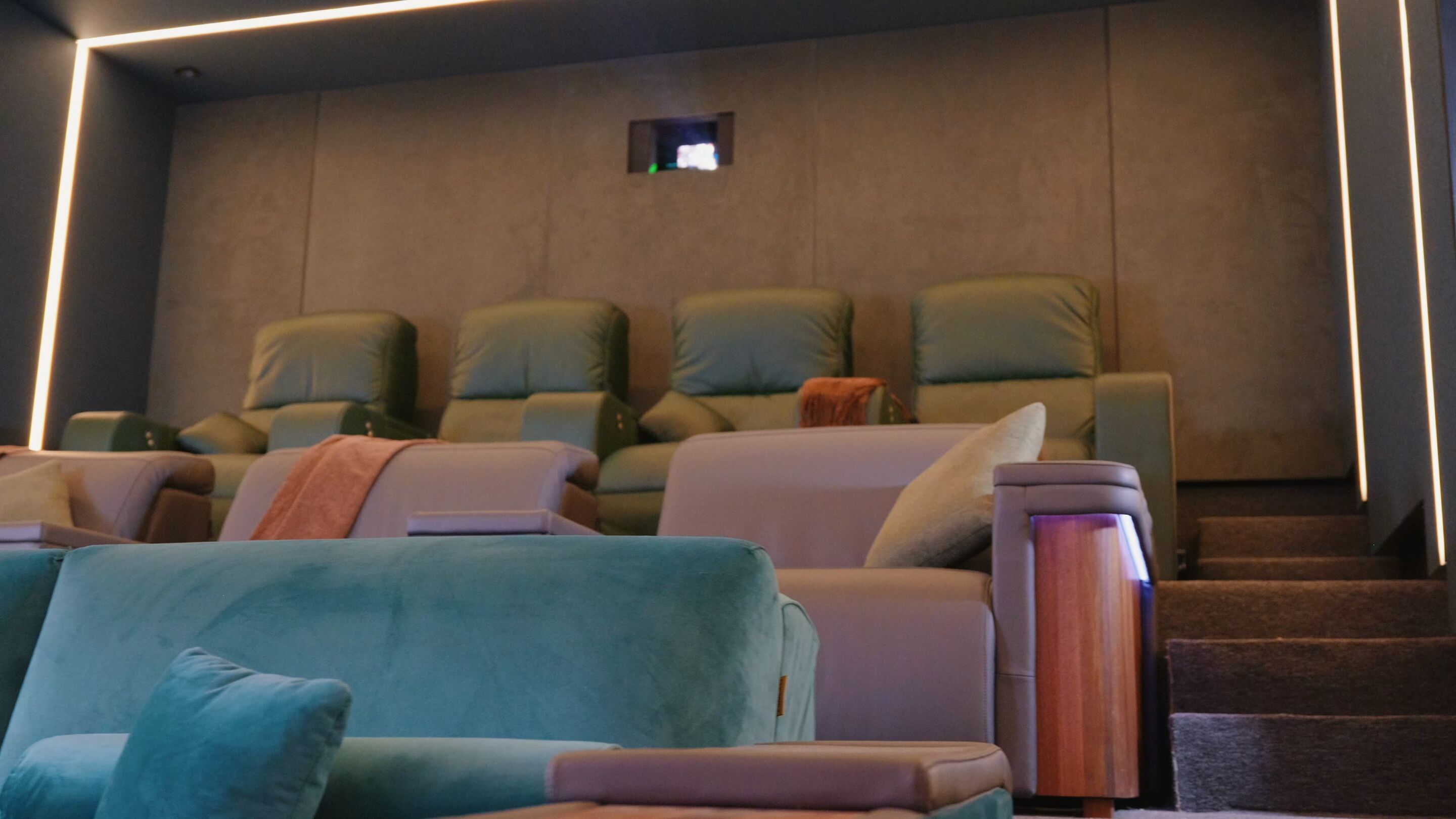 Sala del cine El Maltés con butacas verdes, luz perimetral y el proyector al fondo